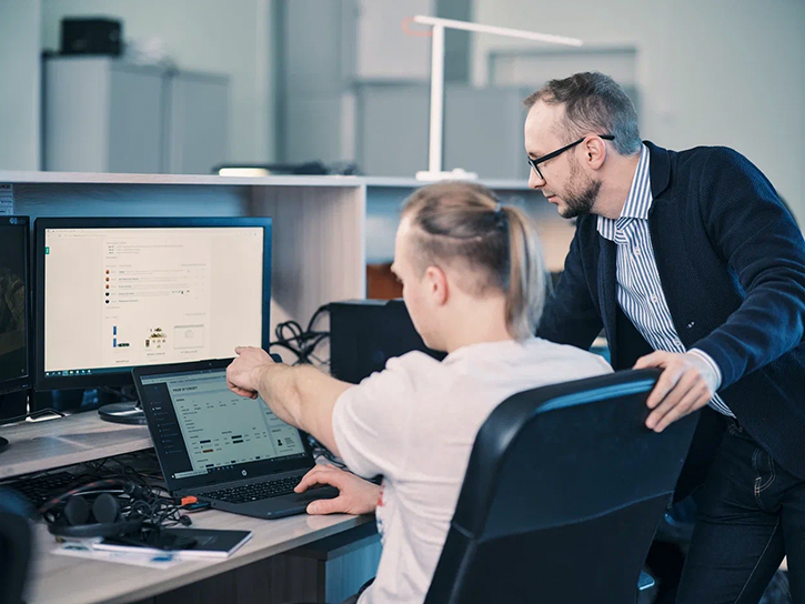 Two Integra Sources specialists discuss the working points while looking at a computer screen.