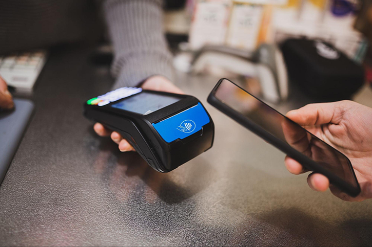A smartphone and an NFC reader used for contactless payment in a store.